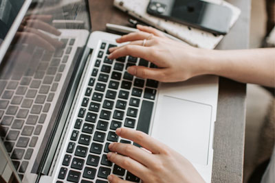 Someone using multiple connected devices, a laptop and phone, requiring the greater Internet speed and bandwidth of Fiber Internet