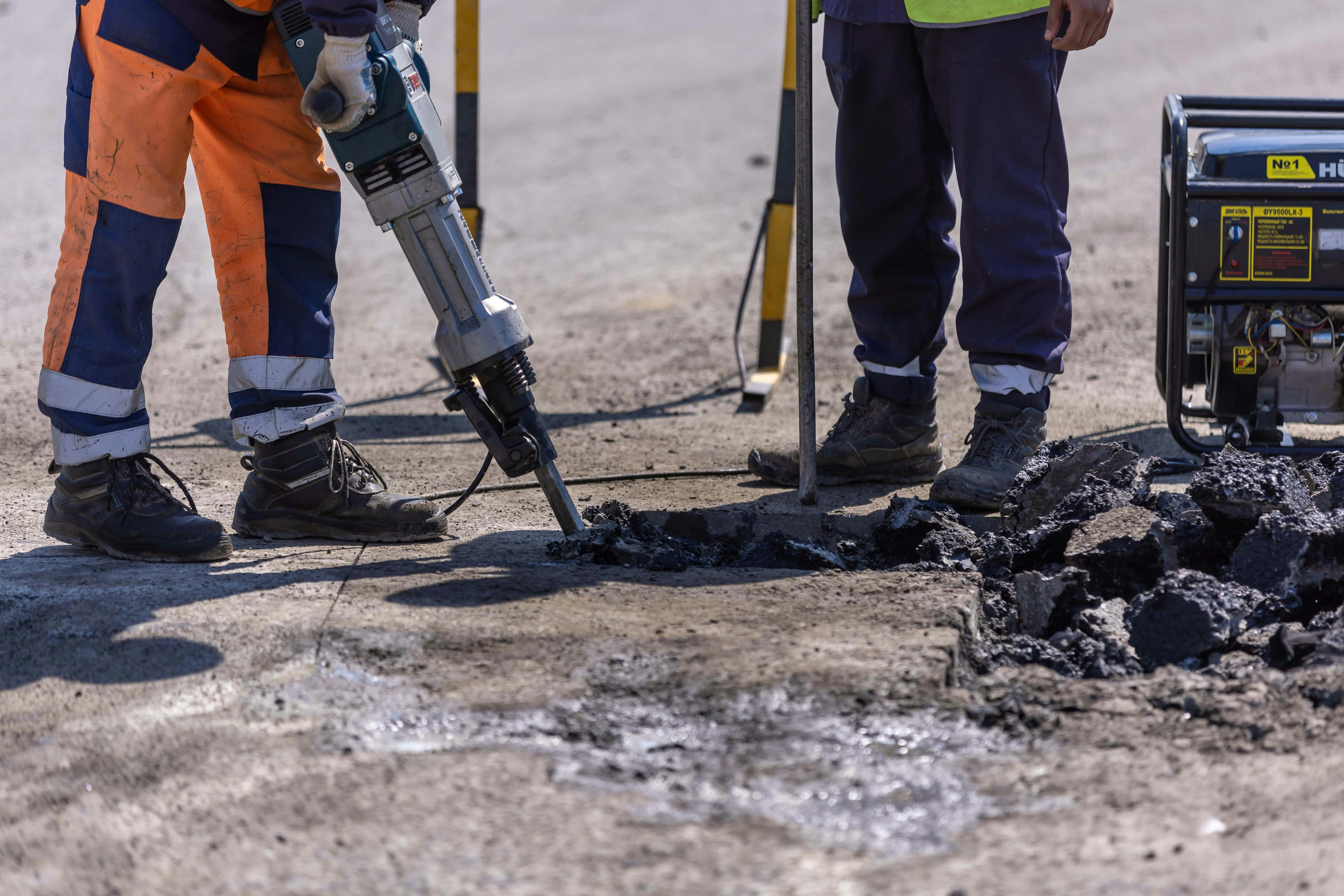 Construction crew breaking pavement to install underground fiber optic cables