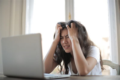 An upset woman looking at her computer