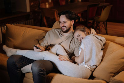A man and woman sitting on the couch watching TV