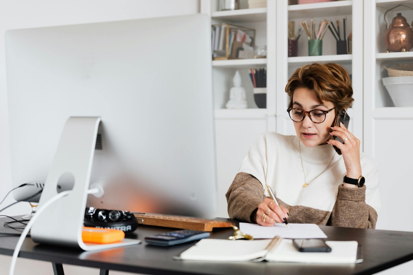 A woman on the phone and taking notes