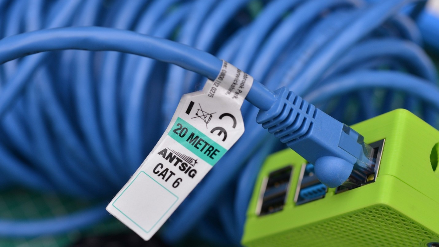 Cat 6 Ethernet cable plugged into optical network terminal for fiber internet connection.