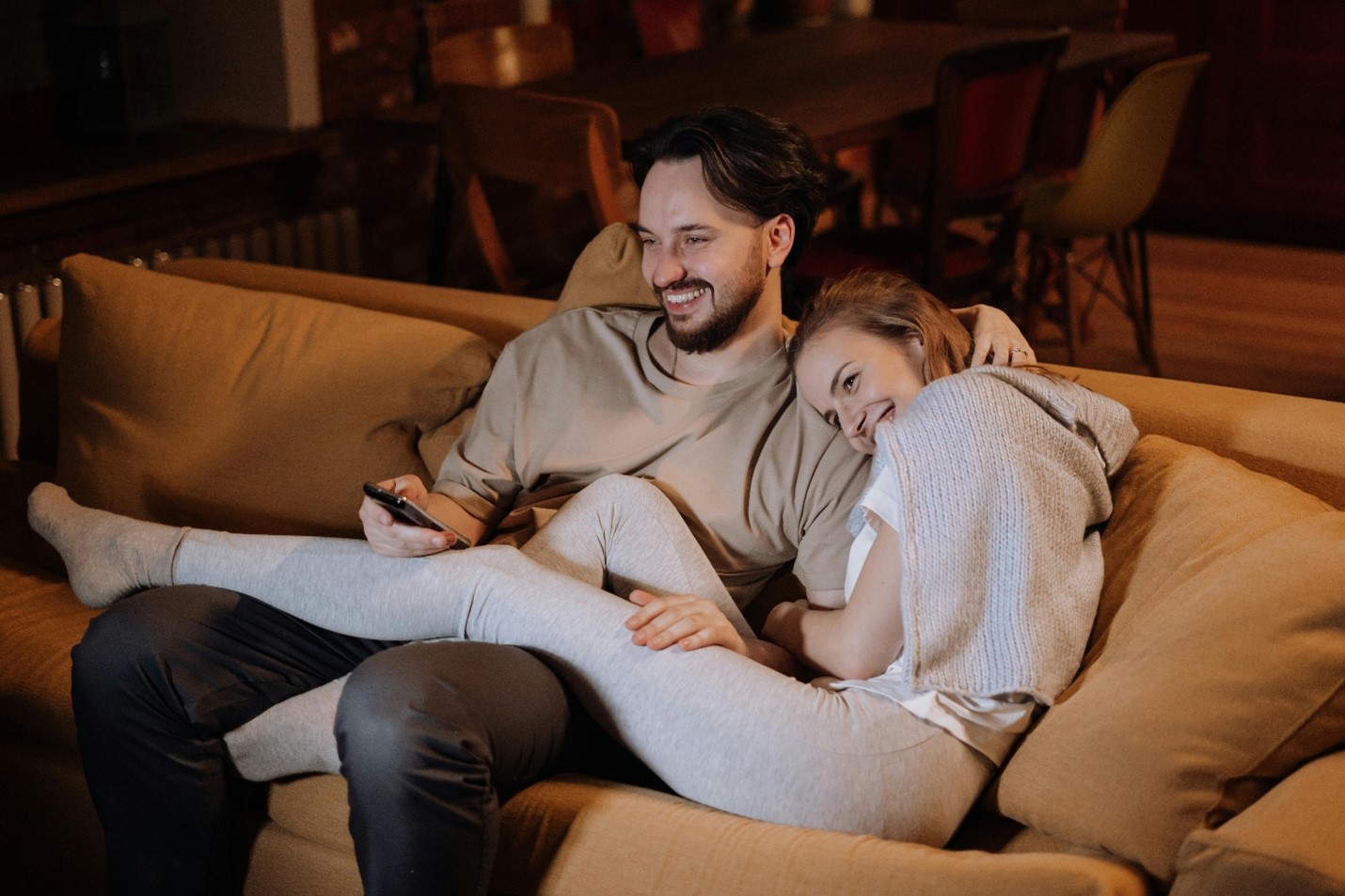 A couple relaxing on a couch and streaming TV together